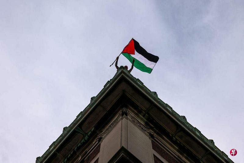 4月30日，一名亲巴勒斯坦示威者在哥伦比亚大学汉密尔顿大楼的屋顶上，举起一面巴勒斯坦国旗。（法新社）