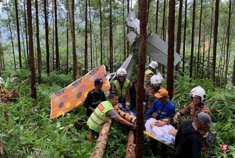 一架训练用的小型飞机坠毁在霹雳州宋溪比索山垦殖区油棕园，救援人员到场后顺利将受伤的飞行教练从飞机残骸中救出。（马新社）