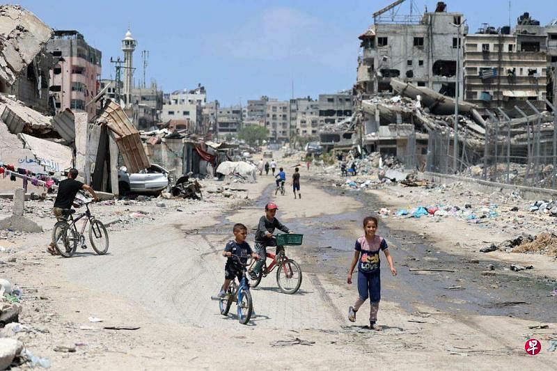 5月3日，几名巴勒斯坦儿童在满目疮痍的加沙市街头骑脚踏车。（法新社）