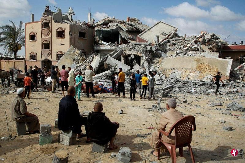 5月5日，在加沙地带南部拉法，巴勒斯坦人看着他们的房屋被以色列袭击。（路透社）