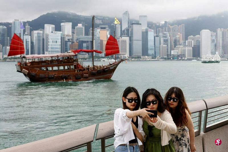 香港文化体育及旅游局局长杨润雄星期一（6月3日）宣布开启“好客之道”运动。图为三名游客4月29日在香港尖沙咀的海滨大道合照。（路透社）