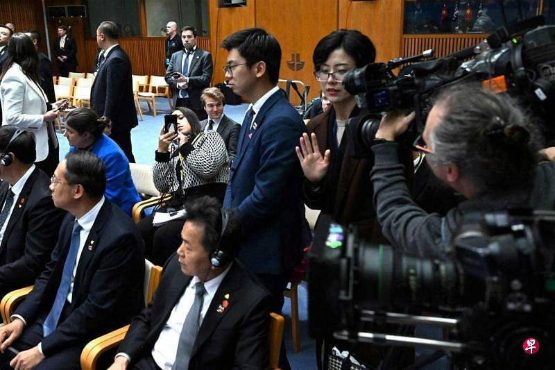 两名中国官员（中左和中右，站立者）6月17日在中澳总理见证合作文件签署的仪式上，站到澳籍华裔记者成蕾（被遮挡）身旁，以阻止现场媒体将她摄入镜头。（法新社）