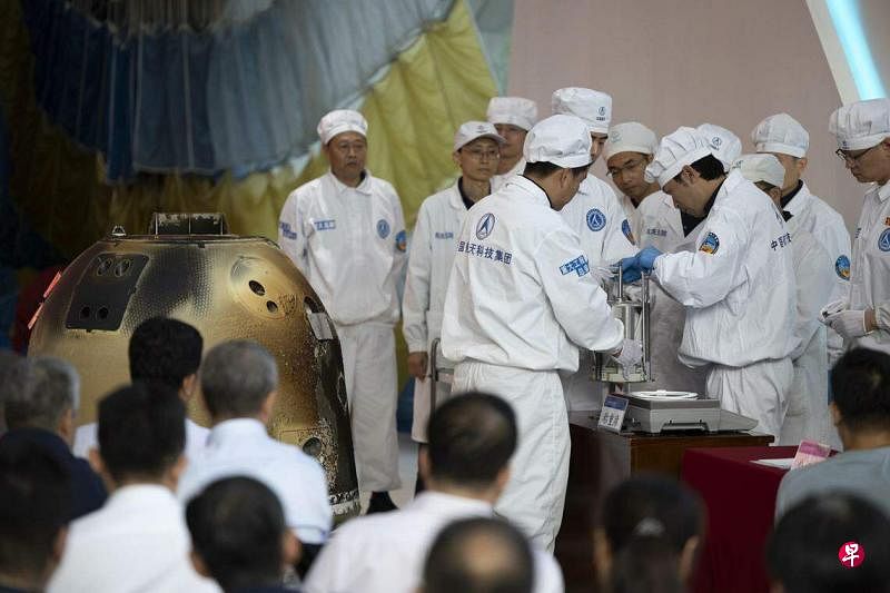 嫦娥六号任务采集月球背面样品1935.3克。图为中国航天科技集团五院6月26日举行嫦娥六号返回器开舱仪式，科研人员对月球样品进行称重。（新华社）