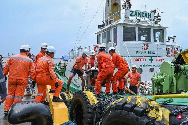 7月26日，海岸警卫队人员在巴丹省利迈的一个港口装载用于处理漏油事故的撇油器。（法新社）