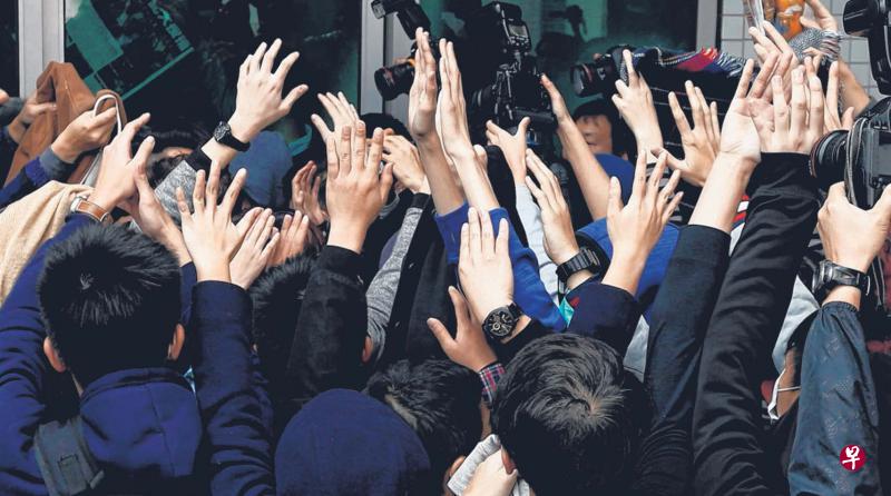 被控参与旺角暴乱的抗议者昨天在法院完成提讯离开时,到场支持者齐齐举手遮挡摄影记者的镜头,不让其容貌曝光。(路透社) 被控参与旺角暴乱的抗议者昨天在法院完成提讯离开时,到场支持者齐齐举手遮挡摄影记者的镜头,不让其容貌曝光。(路透社)