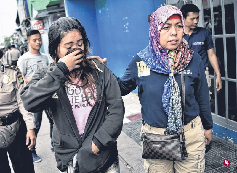 印尼执法人员上周六在雅加达一个红灯区展开扫荡行动时，带走一名疑操丑业的女子（左）。（法新社）
