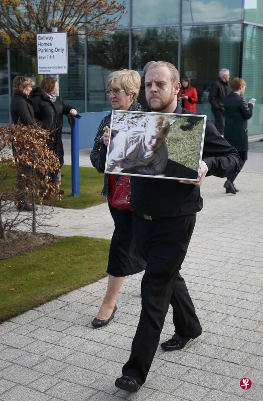 一位死者家属举着亲人的照片前往聆听陪审团的判决。(路透社) 一位死者家属举着亲人的照片前往聆听陪审团的判决。(路透社)