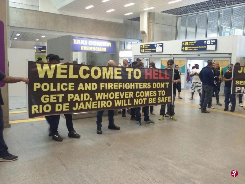 里约警察在加利昂国际机场举起“欢迎来到地狱”的示威横幅,告诉游客警方被欠薪,无法保障他们在里约的人身安全。(互联网) 里约警察在加利昂国际机场举起“欢迎来到地狱”的示威横幅,告诉游客警方被欠薪,无法保障他们在里约的人身安全。(互联网)