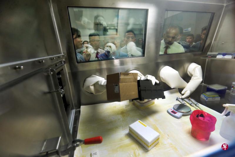 内政部长兼律政部长尚穆根(前右)昨天参观新落成的首个防护分析与评估设施大楼,在可实时分析有害物质的核辐射化验室内聆听工作人员讲解和示范。(谢智扬摄) 内政部长兼律政部长尚穆根(前右)昨天参观新落成的首个防护分析与评估设施大楼,在可实时分析有害物质的核辐射化验室内聆听工作人员讲解和示范。(谢智扬摄)