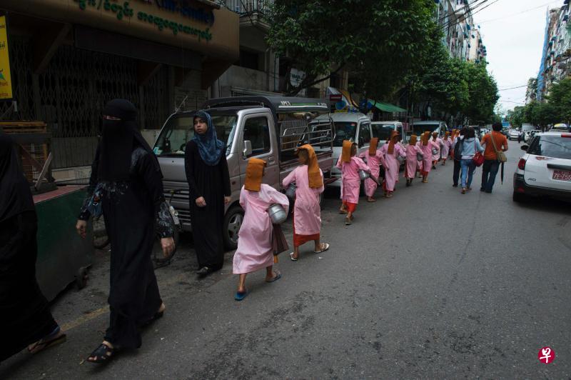 在缅甸最大城市仰光,一群佛教沙弥尼列队沿街化缘,与几名穆斯林女性擦身而过。缅甸新政府近来警告极端僧侣不要继续发表针对穆斯林居民的煽动性言论。(法新社) 在缅甸最大城市仰光,一群佛教沙弥尼列队沿街化缘,与几名穆斯林女性擦身而过。缅甸新政府近来警告极端僧侣不要继续发表针对穆斯林居民的煽动性言论。(法新社)