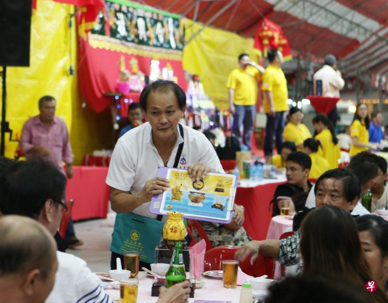 多年来,义工佘福财都会在这段期间为大众医院筹款活动献力,到中元节晚宴沿桌募捐和义卖福物。(梁伟康摄) 多年来,义工佘福财都会在这段期间为大众医院筹款活动献力,到中元节晚宴沿桌募捐和义卖福物。(梁伟康摄)
