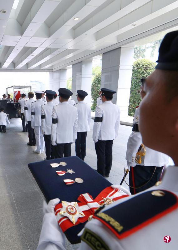 扶灵队将盖上国旗的灵柩放进拖曳炮架上的钢化玻璃保护外壳,准备开离国会大厦,前往举行国葬仪式的国大文化中心。(何家俊摄) 扶灵队将盖上国旗的灵柩放进拖曳炮架上的钢化玻璃保护外壳,准备开离国会大厦,前往举行国葬仪式的国大文化中心。(何家俊摄)