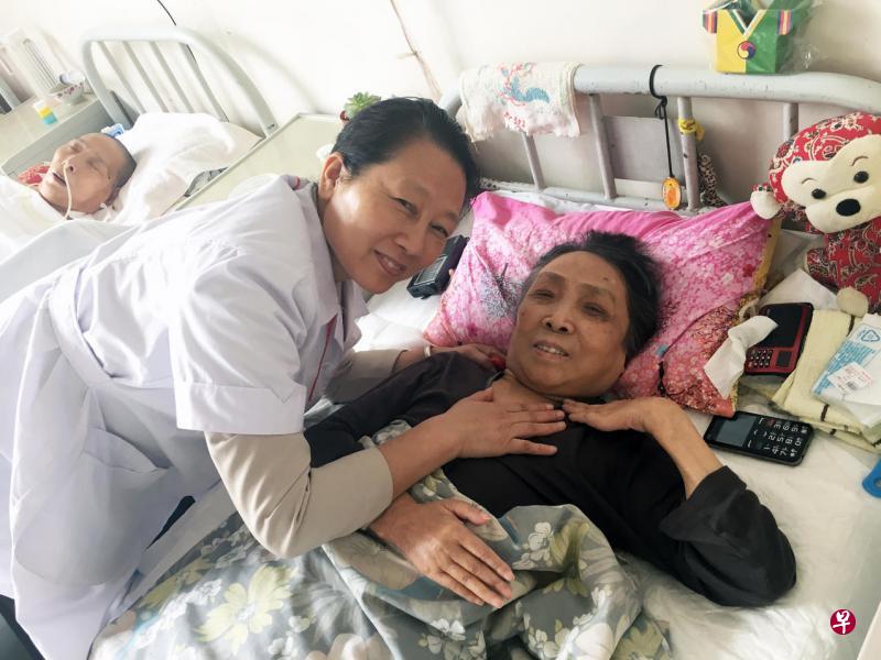 现年75岁的张贞娥（右）九年前入住松堂关怀医院接受专人照料，中为医院院办主任静佩君。（林子恒摄）