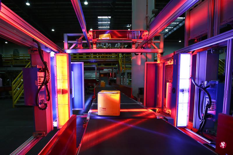 敦豪南亚枢纽使用一种六方位照相机扫描与称重量系统,把扫描条码与衡量包裹大小的工作自动化,减除这方面所需的人工。(陈斌勤摄) 敦豪南亚枢纽使用一种六方位照相机扫描与称重量系统,把扫描条码与衡量包裹大小的工作自动化,减除这方面所需的人工。(陈斌勤摄)