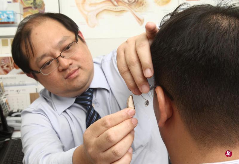 The Hearing Specialist Clinic首席听力专家陈文海(左)为听障者佩戴现代智慧型助听器。(档案照) The Hearing Specialist Clinic首席听力专家陈文海(左)为听障者佩戴现代智慧型助听器。(档案照)