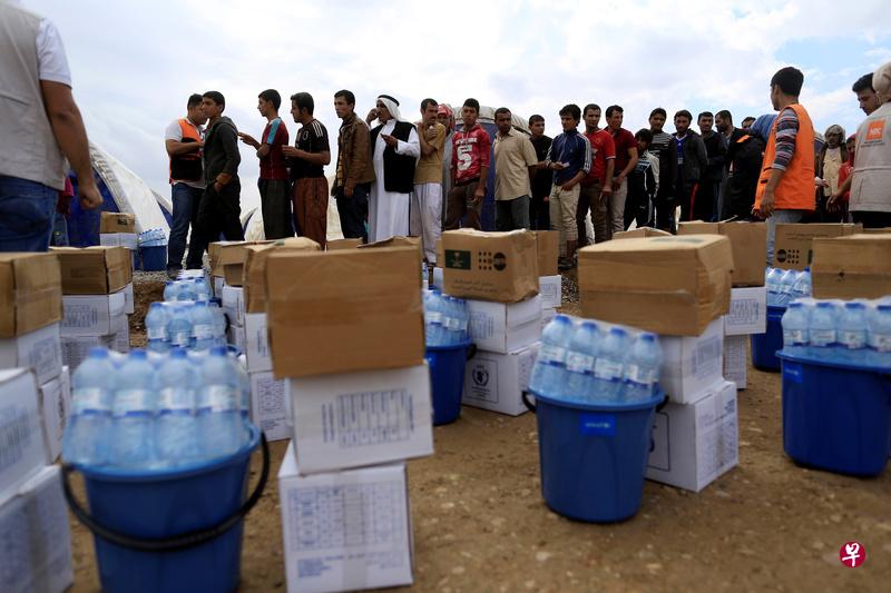 从摩苏尔逃出来的平民等着领取救援物资。(路透社) 从摩苏尔逃出来的平民等着领取救援物资。(路透社)