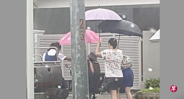 两名圣尼各拉女校的女生背着书包,由母亲撑伞,冒 雨帮老妇解困。(Stomp) 两名圣尼各拉女校的女生背着书包,由母亲撑伞,冒 雨帮老妇解困。(Stomp)