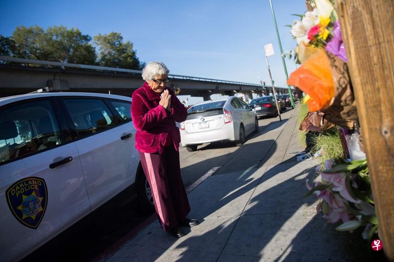 一名奥克兰市民在火灾现场附近为遇难者祷告。(法新社) 一名奥克兰市民在火灾现场附近为遇难者祷告。(法新社)