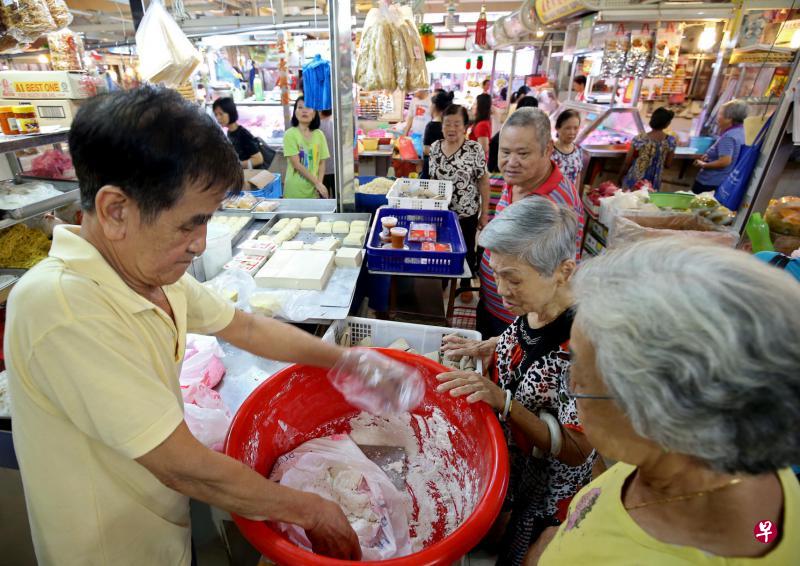 售卖糯米粉泥已有50多年摊贩陈长福（左）说：“购买糯米粉泥回家自己动手搓汤圆的顾客，大部分是60岁及以上的老一辈人。”
