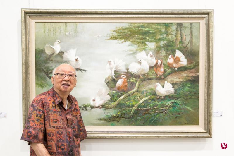 画家朱庆光说，年纪大了，尽量争取时间多做展览。背后是2015年创作的鸽画《和谐》。