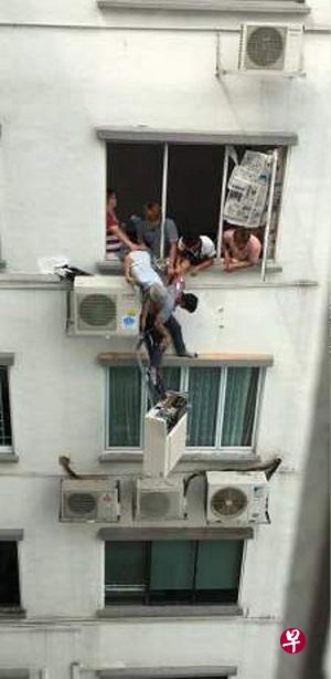 冷气安装员在窗外悬空,众人合力拉住他,惊险万分。(图/取自网络) 冷气安装员在窗外悬空,众人合力拉住他,惊险万分。(图/取自网络)