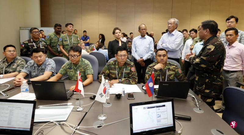 国防部长黄永宏(后排右二)、菲律宾国防部长罗伦沙纳(Delfin Lorenzana,后排右三)以及美国驻新加坡大使馆代办斯蒂芬妮(Stephanie Syptak-Ramnath,后排右四)昨天在樟宜海军基地内的多国指挥与控制中心视察沙盘推演情况。(海峡时报) 国防部长黄永宏(后排右二)、菲律宾国防部长罗伦沙纳(Delfin Lorenzana,后排右三)以及美国驻新加坡大使馆代办斯蒂芬妮(Stephanie Syptak-Ramnath,后排右四)昨天在樟宜海军基地内的多国指挥与控制中心视察沙盘推演情况。(海峡时报)