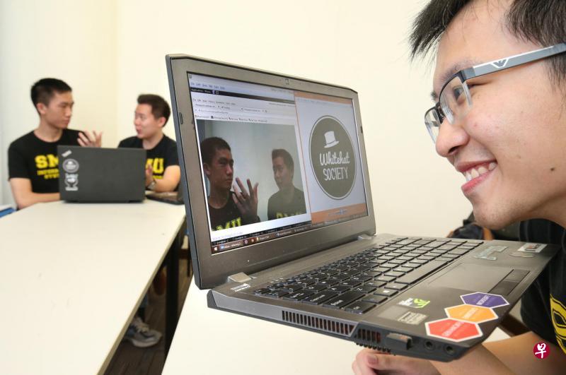 新加坡管理大学“白帽黑客学会”通过示范网络入侵技术，提高人们的网络安全意识。图为白帽黑客学会主席黄伟德（右一）示范电脑下载含有恶意软件的电子附件后，“黑帽黑客”可操控被入侵电脑的网络摄像机，对受害人进行监视。图中被“监视”的是白帽黑客学会副主席何明杰（左一）和秘书林健全。（何家俊摄）