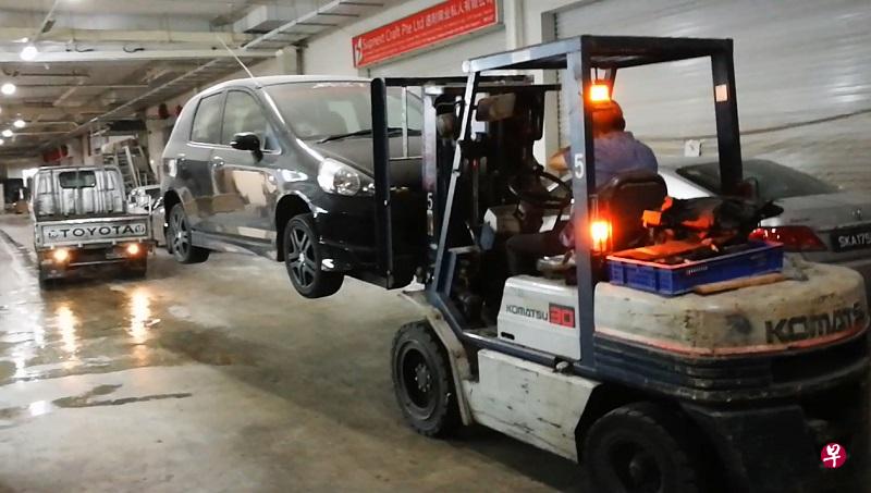 职员利用叉车抬起掀背车。 职员利用叉车抬起掀背车。