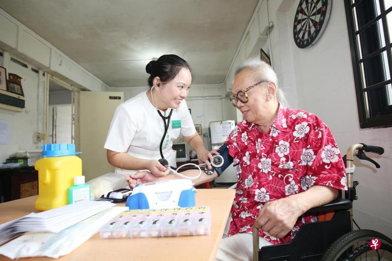 新加坡中央医院高级护士蓝千美(左)定期到年长病患王弗安的住家,为他量血压、血糖和做护理,让他能在家中安心疗养。(周柏荣摄) 新加坡中央医院高级护士蓝千美(左)定期到年长病患王弗安的住家,为他量血压、血糖和做护理,让他能在家中安心疗养。(周柏荣摄)