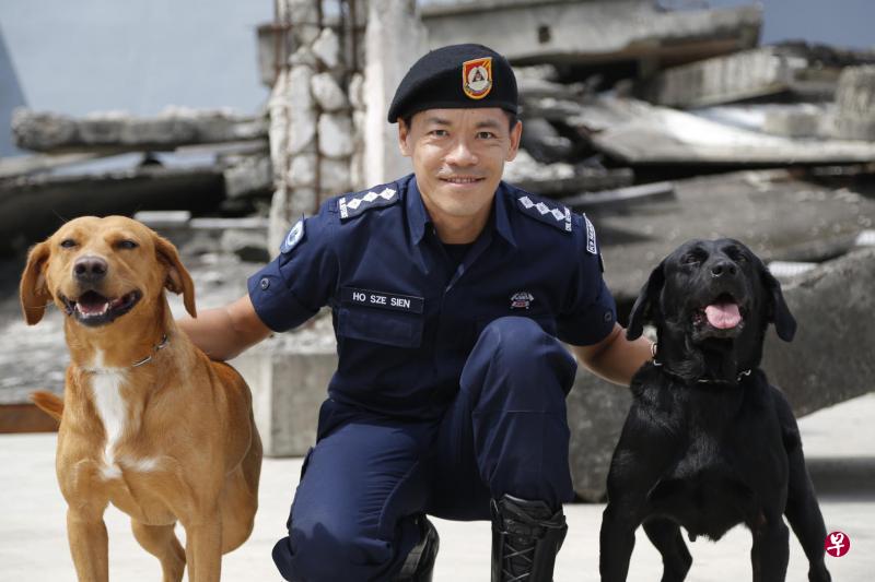 民防部队灵犬搜寻队指挥官何思省上校与他培训的两只拉布拉多犬Rua(左)和Jade(右)。何思省希望将来能领养一只退休灵犬。(民防部队提供) 民防部队灵犬搜寻队指挥官何思省上校与他培训的两只拉布拉多犬Rua(左)和Jade(右)。何思省希望将来能领养一只退休灵犬。(民防部队提供)
