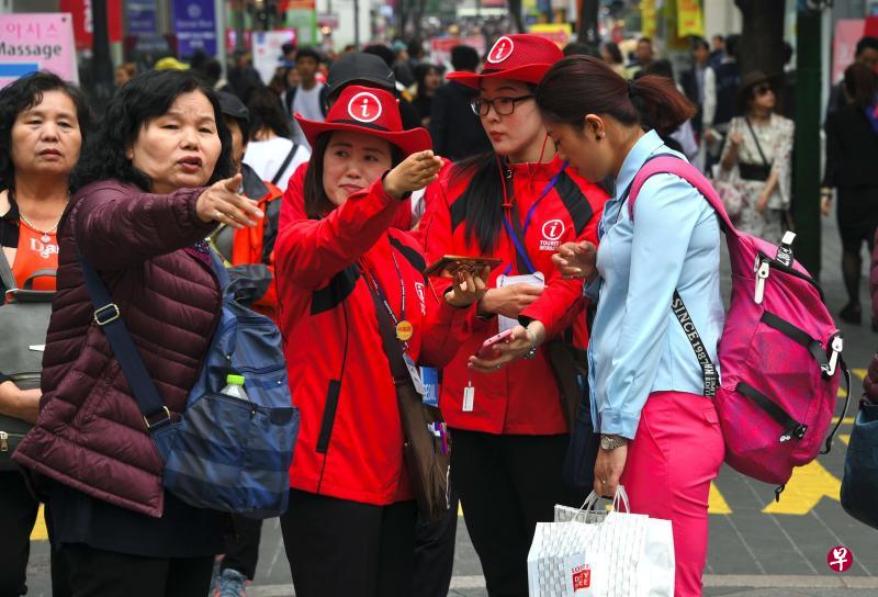 4月25日,韩国旅游信息工作人员(红衣)在首尔的明洞购物区引导游客。(法新社) 4月25日,韩国旅游信息工作人员(红衣)在首尔的明洞购物区引导游客。(法新社)
