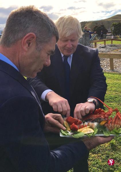 约翰逊(右)24日访问新西兰南岛城镇凯库拉,与新西兰民防部长盖伊(左)一起享用新鲜的小龙虾。(路透社) 约翰逊(右)24日访问新西兰南岛城镇凯库拉,与新西兰民防部长盖伊(左)一起享用新鲜的小龙虾。(路透社)