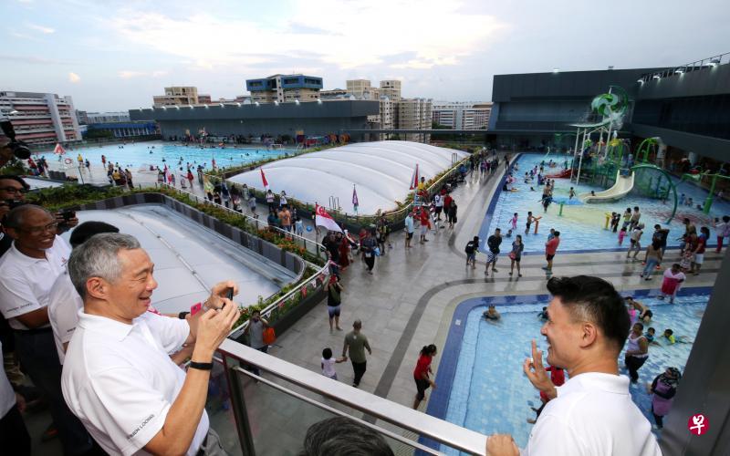 李显龙总理(左)昨天为淡滨尼天地主持正式揭幕仪式。图为总理在开幕仪式前参观淡滨尼天地顶层的游泳池设施时,用手机为文化、社区及青年部政务次长马炎庆拍照留念。(邝启聪摄) 李显龙总理(左)昨天为淡滨尼天地主持正式揭幕仪式。图为总理在开幕仪式前参观淡滨尼天地顶层的游泳池设施时,用手机为文化、社区及青年部政务次长马炎庆拍照留念。(邝启聪摄)