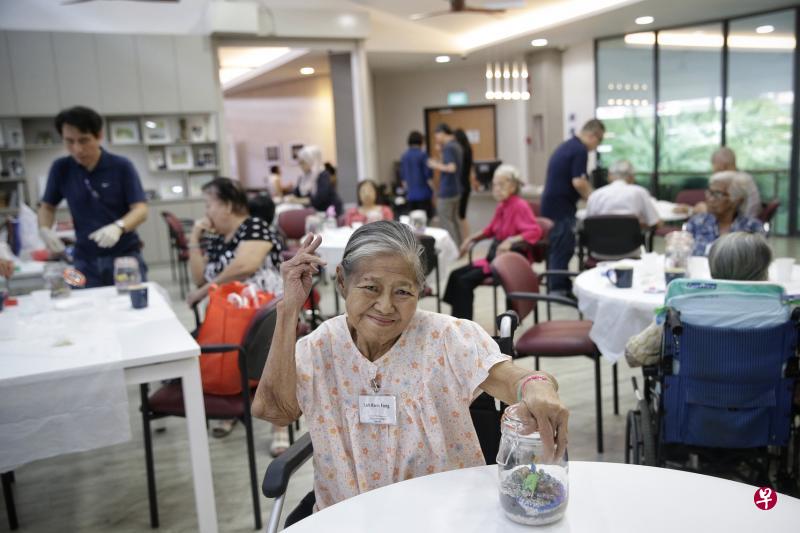 卢桂芳在黄埔民众俱乐部内的丰盛乐龄社区综合服务中心进行多项活动,包括亲手制作桌上的瓶中景。(海峡时报) 卢桂芳在黄埔民众俱乐部内的丰盛乐龄社区综合服务中心进行多项活动,包括亲手制作桌上的瓶中景。(海峡时报)