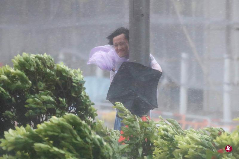 香港一名男子紧抱灯柱,才免于被强烈台风“天鸽”吹走。(路透社) 香港一名男子紧抱灯柱,才免于被强烈台风“天鸽”吹走。(路透社)