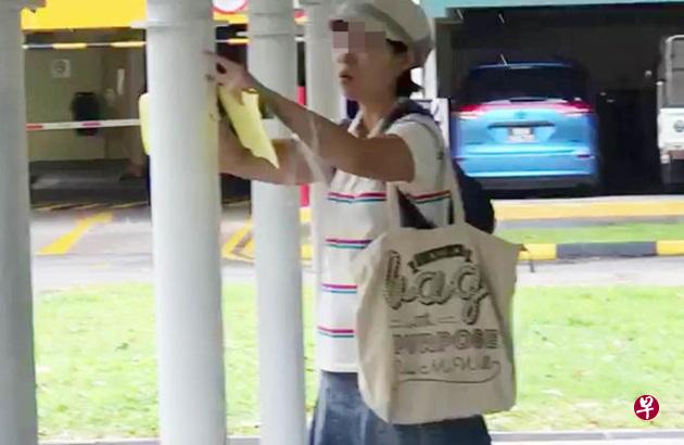 女子在组屋楼下有盖走道的柱子上张贴“个人贷款”广告。(视频截图) 女子在组屋楼下有盖走道的柱子上张贴“个人贷款”广告。(视频截图)