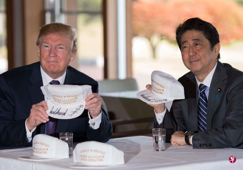 日本首相安倍晋三（右）在东京市郊埼玉县川越市霞关乡村俱乐部同到访的美国总统特朗普共进午餐后，一起打高尔夫，两人还在一些印有“特朗普和安倍使美日同盟更加伟大”字样的帽子上签名留念。（法新社）