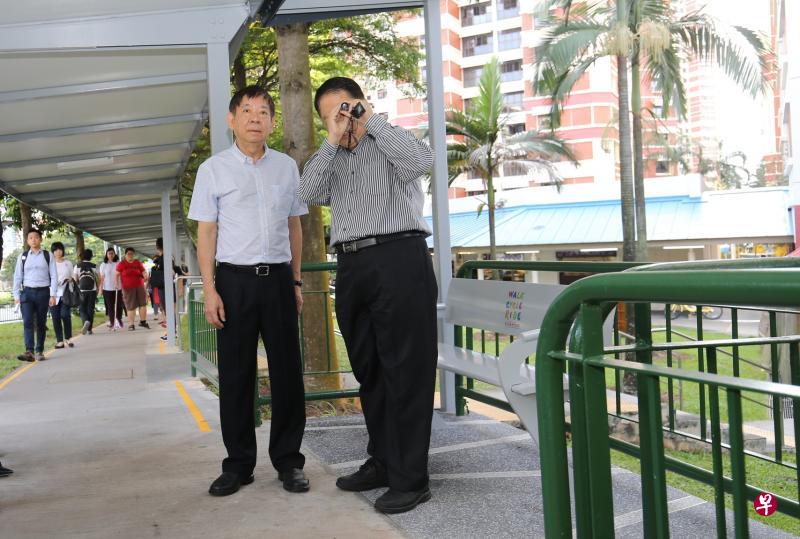 患有视觉障碍的卓振益(右)昨天与基础建设统筹部长兼交通部长许文远(左)试用无障碍有盖走廊时,示范如何使用视力辅助工具查看告示牌。(谢智扬摄) 患有视觉障碍的卓振益(右)昨天与基础建设统筹部长兼交通部长许文远(左)试用无障碍有盖走廊时,示范如何使用视力辅助工具查看告示牌。(谢智扬摄)