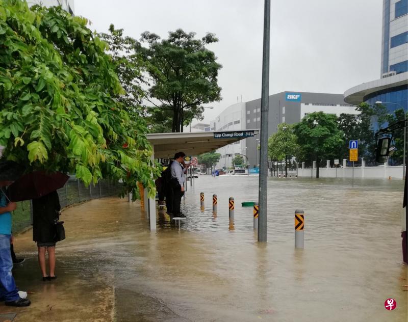 豪雨骤降，多条道路发生突发性淹水。一些公众只好站在巴士站的椅子上等巴士。（读者提供）