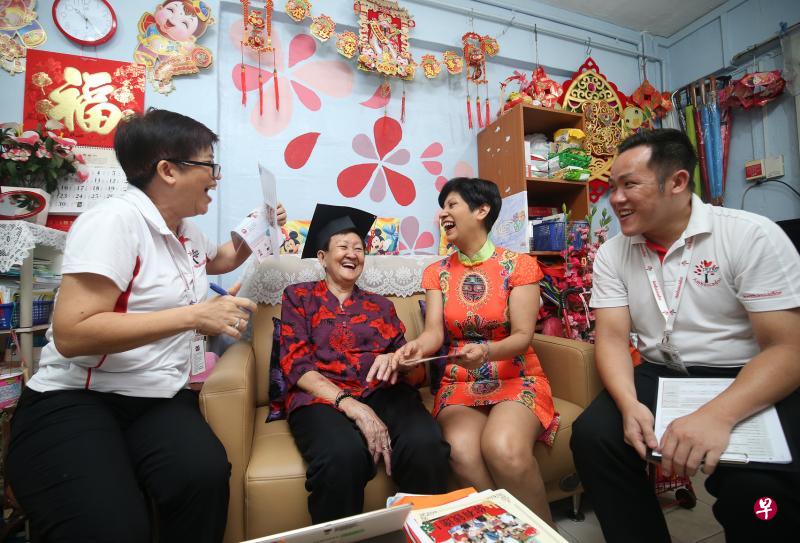 律政部兼财政部高级政务部长英兰妮（右二），昨早与建国一代大使走访德惠巷居民蔡来钻（右三），向她讲解如何参加各种社区活动。（叶振忠摄）