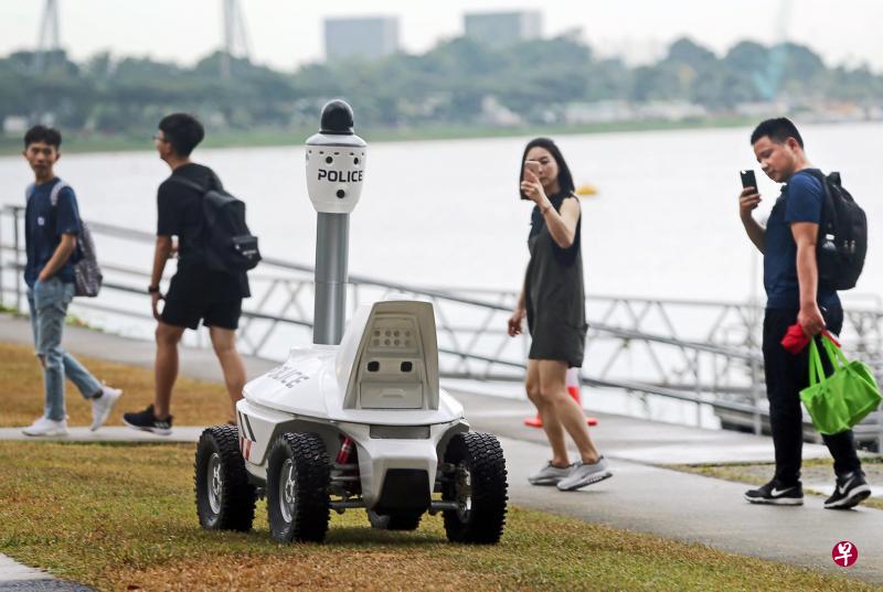新加坡警察部队和业界联手研发的“巡逻机器人”,昨天下午出现在摩天观景轮附近的妆艺大游行现场,引起公众好奇,纷纷掏出手机拍下机器人的模样。(林国明摄) 新加坡警察部队和业界联手研发的“巡逻机器人”,昨天下午出现在摩天观景轮附近的妆艺大游行现场,引起公众好奇,纷纷掏出手机拍下机器人的模样。(林国明摄)