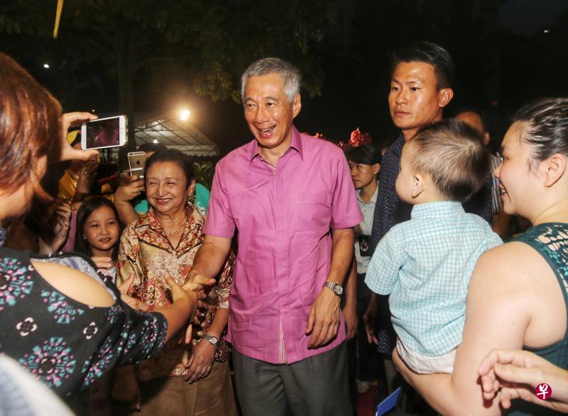 李显龙总理(中)出席德义区新春晚宴时,与许多热情迎接的居民握手合照。(林国明摄) 李显龙总理(中)出席德义区新春晚宴时,与许多热情迎接的居民握手合照。(林国明摄)