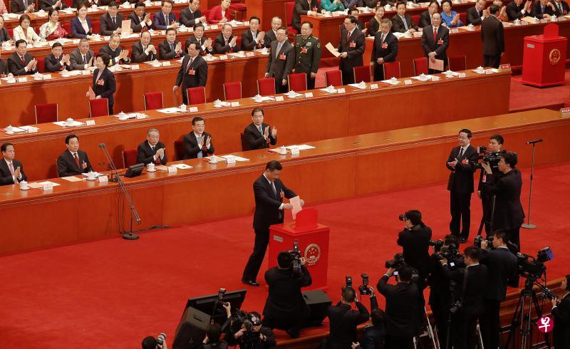 中共总书记、中国国家主席习近平将粉红色的表决票投入投票箱时,现场响起热烈掌声。左小图为人民大会堂会场前方的电子屏幕显示了修宪草案的表决结果。(路透社/彭博社) 中共总书记、中国国家主席习近平将粉红色的表决票投入投票箱时,现场响起热烈掌声。左小图为人民大会堂会场前方的电子屏幕显示了修宪草案的表决结果。(路透社/彭博社)