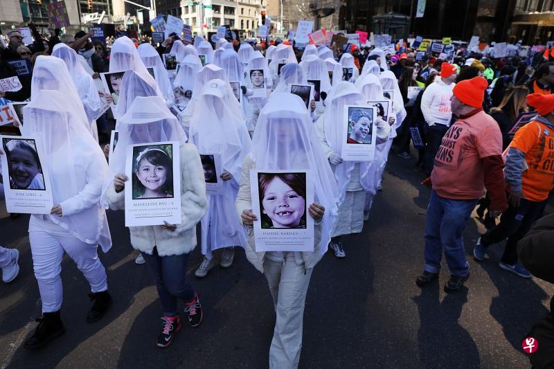 数以千计的示威者在周六举行的大规模控枪游行活动中,手持枪击案受害者的照片。(法新社) 数以千计的示威者在周六举行的大规模控枪游行活动中,手持枪击案受害者的照片。(法新社)