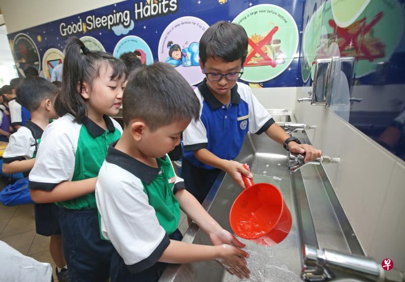 国专长老会小学昨早举行制水演习,学生用餐前,从塑料桶中取出有限的水洗手。(叶振忠摄) 国专长老会小学昨早举行制水演习,学生用餐前,从塑料桶中取出有限的水洗手。(叶振忠摄)