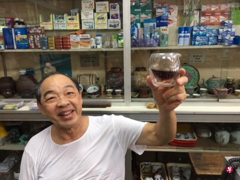 金宝“广元泉记药庄茶行”的黄老板举起一杯“金花六堡”说:你们看,是cognac(干邑)的颜色。(林方伟摄) 金宝“广元泉记药庄茶行”的黄老板举起一杯“金花六堡”说:你们看,是cognac(干邑)的颜色。(林方伟摄)