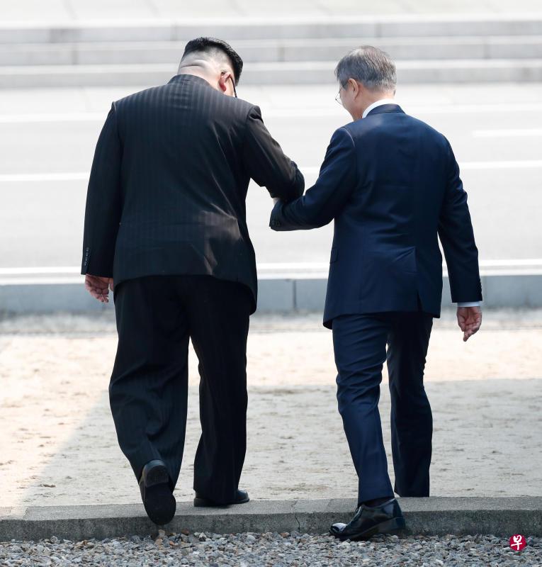 金正恩牵着文在寅的手跨入朝鲜境内。(路透社) 金正恩牵着文在寅的手跨入朝鲜境内。(路透社)
