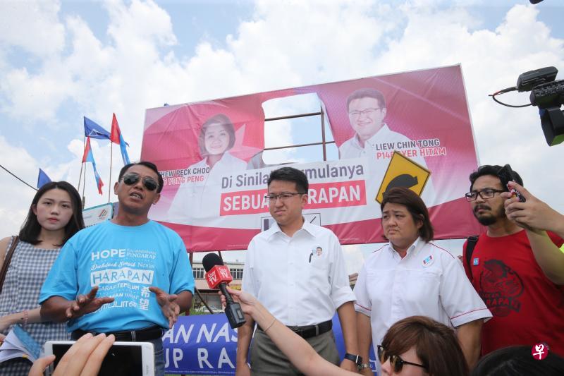 选委会官员剪去希盟大型看板的马哈迪肖像和名字而留下一个破洞。(邝启聪摄) 选委会官员剪去希盟大型看板的马哈迪肖像和名字而留下一个破洞。(邝启聪摄)