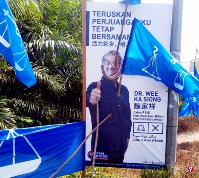 魏家祥竞选看板上的肖像不只遭人贴上马哈迪的“面具”,肖像的眼睛和心脏还遭树枝刺穿。(星洲日报) 魏家祥竞选看板上的肖像不只遭人贴上马哈迪的“面具”,肖像的眼睛和心脏还遭树枝刺穿。(星洲日报)