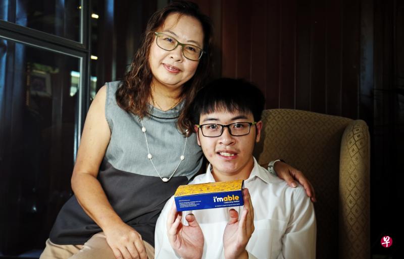 自闭艺术家叶晋晖(右)以沙爹、螃蟹和黄梨挞等本地美食为灵感,设计出可在新航经济舱使用的纸制小吃盒。图为他和母亲巫爱娣的合照。(邬福梁摄) 自闭艺术家叶晋晖(右)以沙爹、螃蟹和黄梨挞等本地美食为灵感,设计出可在新航经济舱使用的纸制小吃盒。图为他和母亲巫爱娣的合照。(邬福梁摄)